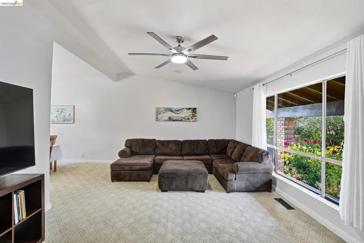 Carpeted living area with vaulted ceiling and a ceiling fan