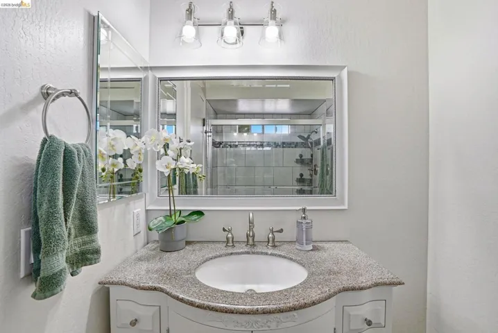 Bathroom featuring vanity, a textured wall, and a shower stall