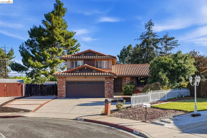 Mediterranean / spanish home with a tile roof, concrete driveway, an attached garage, and brick siding