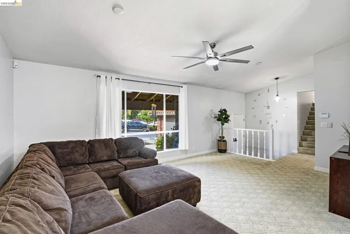 Living area featuring ceiling fan, light colored carpet, and vaulted ceiling