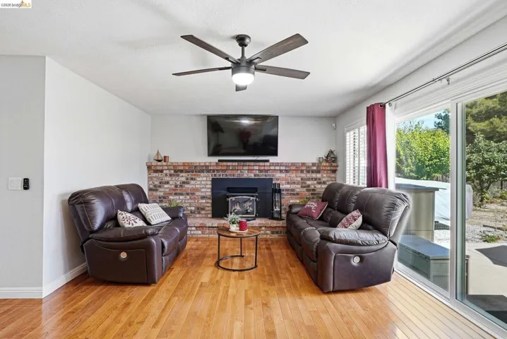 Living area featuring hardwood / wood-style flooring, ceiling fan, and a fireplace