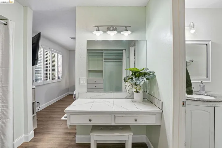 Bathroom featuring vanity, dark wood-style floors, a spacious closet, and a shower with shower curtain