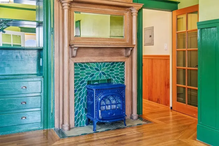Detailed view of a wood stove, wood finished floors, a wainscoted wall, electric panel, and wood walls
