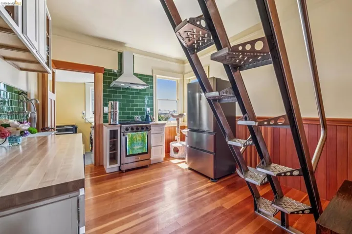 Kitchen with wooden counters, stainless steel appliances, exhaust hood, light wood-type flooring, and ornamental molding