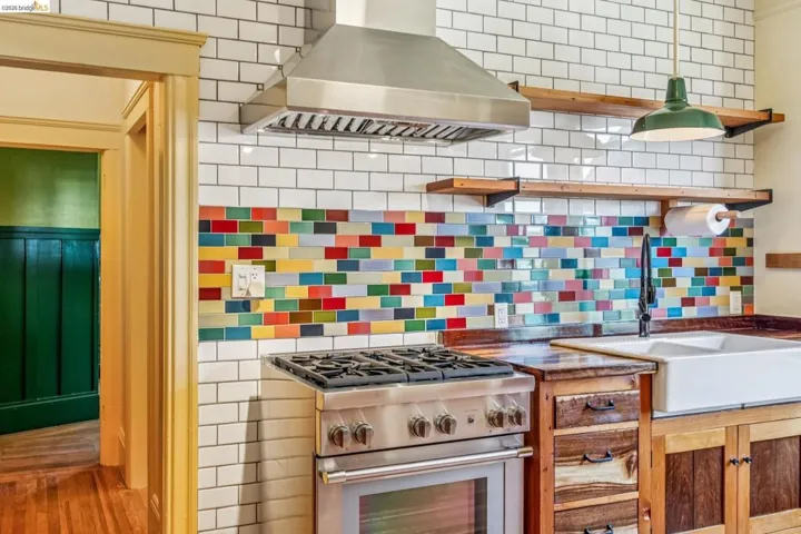 Kitchen with exhaust hood, high end range, open shelves, dark countertops, and decorative backsplash