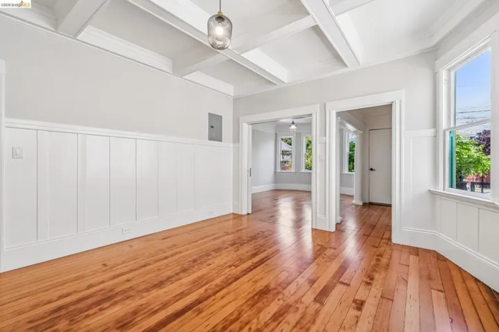Unfurnished room with wainscoting, coffered ceiling, a decorative wall, light wood-style flooring, and crown molding