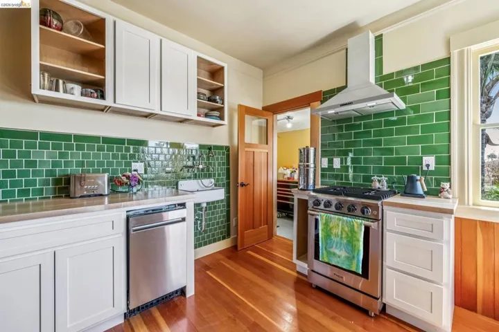 Kitchen with white cabinetry, stainless steel appliances, extractor fan, open shelves, and light wood finished floors