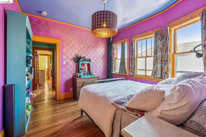 Bedroom with wood finished floors and wallpapered walls