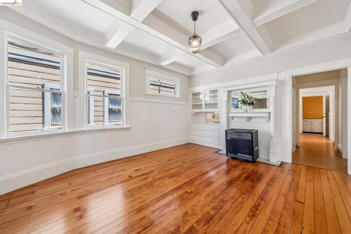 Unfurnished living room with hardwood / wood-style flooring, coffered ceiling, a wainscoted wall, and a decorative wall