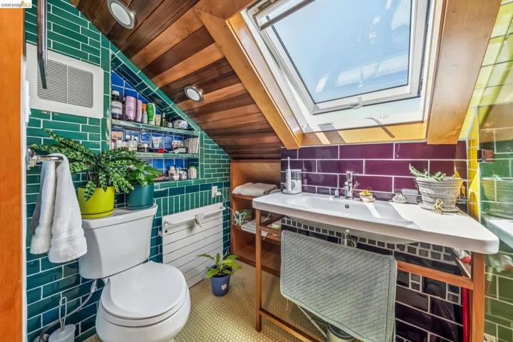 Bathroom featuring a skylight, a vaulted wooden ceiling, and tile walls