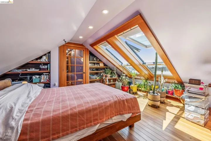 Bedroom with a skylight, lofted ceiling, recessed lighting, and wood-type flooring