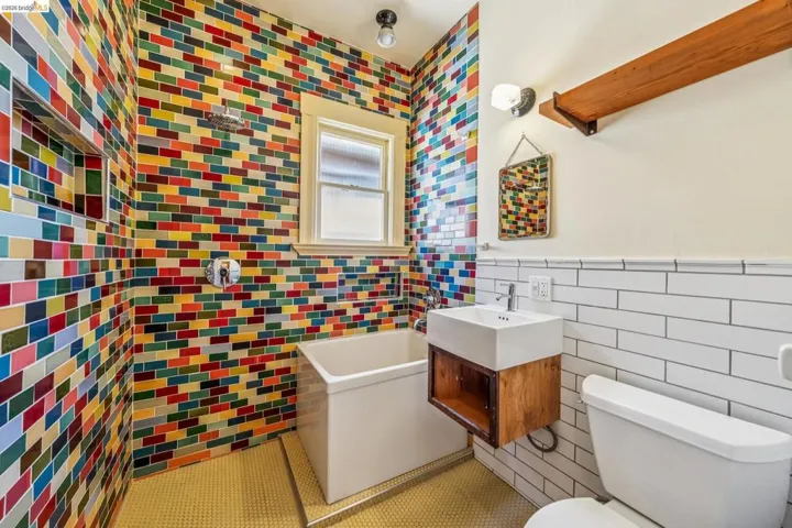 Full bath with tile walls, a soaking tub, vanity, a wainscoted wall, and tile patterned flooring