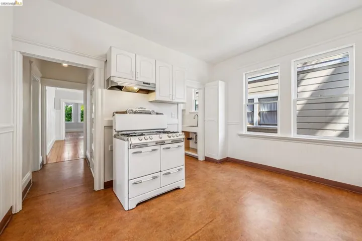 Kitchen with white cabinets, range with two ovens, and finished concrete floors