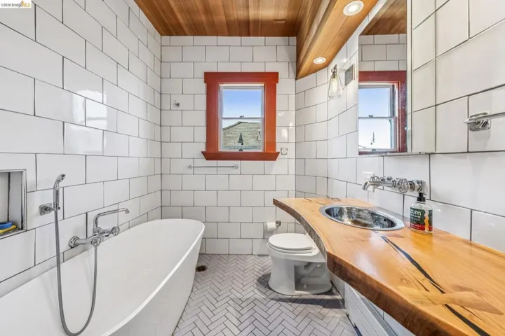 Bathroom featuring a soaking tub, vanity, tile walls, and light tile patterned flooring