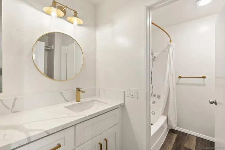 Remodeled bathroom w/ new vanity, quartz countertops, sink, lighting and mirror, fresh epoxy-coated bathtub/shower surround.