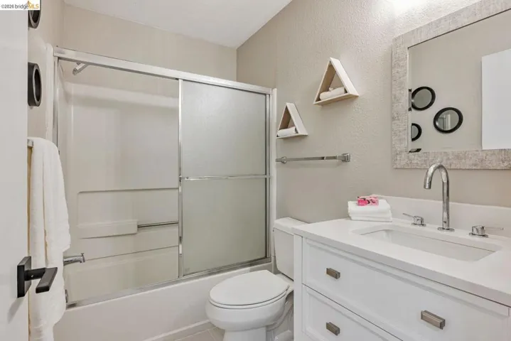 bathroom featuring vanity, enclosed tub / shower combo, and a textured wall