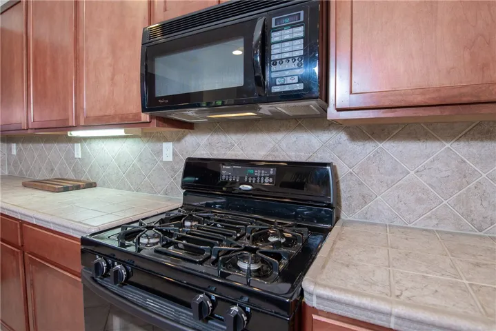 The black appliances highlight the beautifully maintained tan tile countertop.