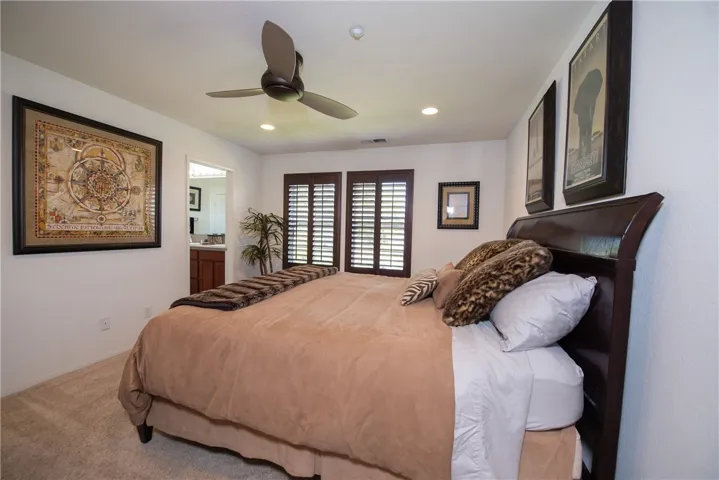 The primary bedroom has large windows with rich wood shutters and a ceiling fan to keep you cool on those warm days.