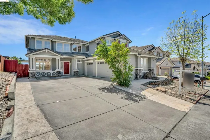 View of front of property featuring stone siding, driveway, stucco siding, an attached garage, and a residential view