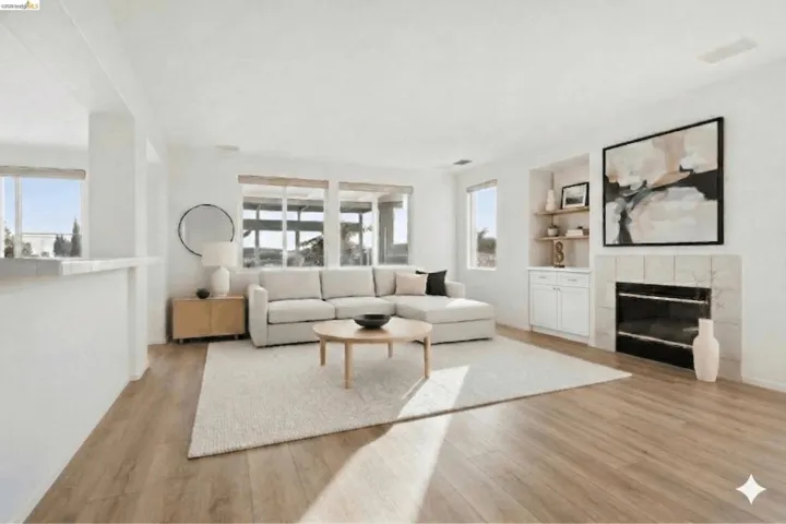 Living area with a fireplace, built in shelves, light wood-style floors, and plenty of natural light