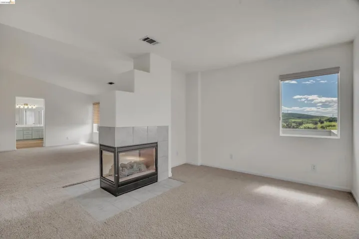 Unfurnished living room featuring a fireplace and light colored carpet