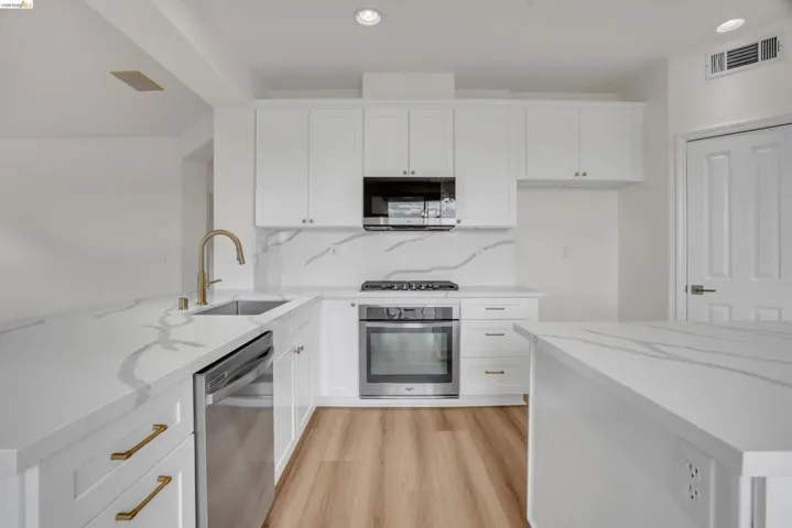 Kitchen with white cabinets, stainless steel appliances, and recessed lighting