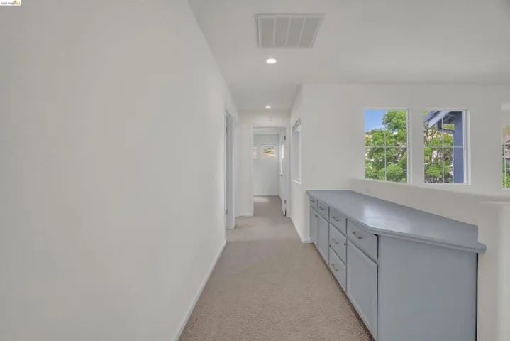 Corridor with light carpet and recessed lighting