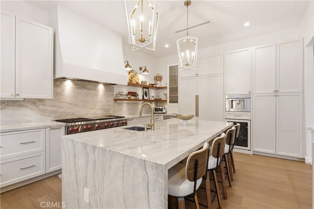 Luxury designer kitchen w/ barstool seating, birdcage pendants, 60 inch double oven Wolf range and high ceilings.