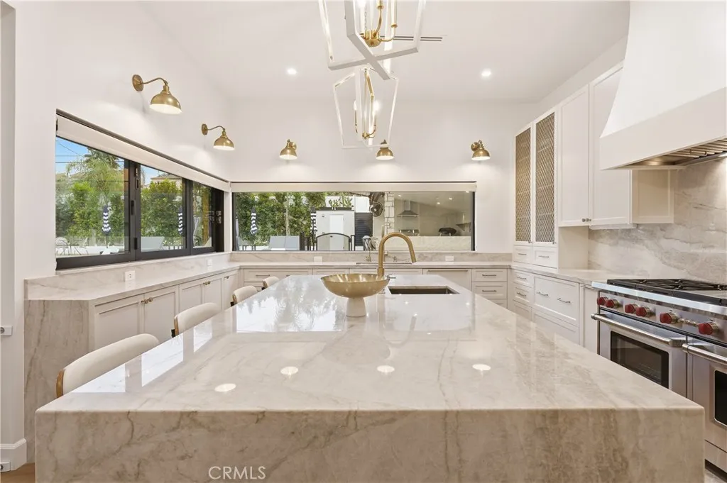 Oversized Taj Mahal Quartzite waterfall island with sink, dishwasher & trash bin drawer.