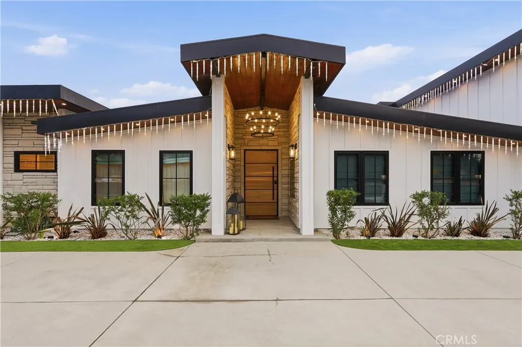 Grand front foyer wrapped in stone with a two-tiered rustic chandelier, complemented by two posts and low maintenance landscape!