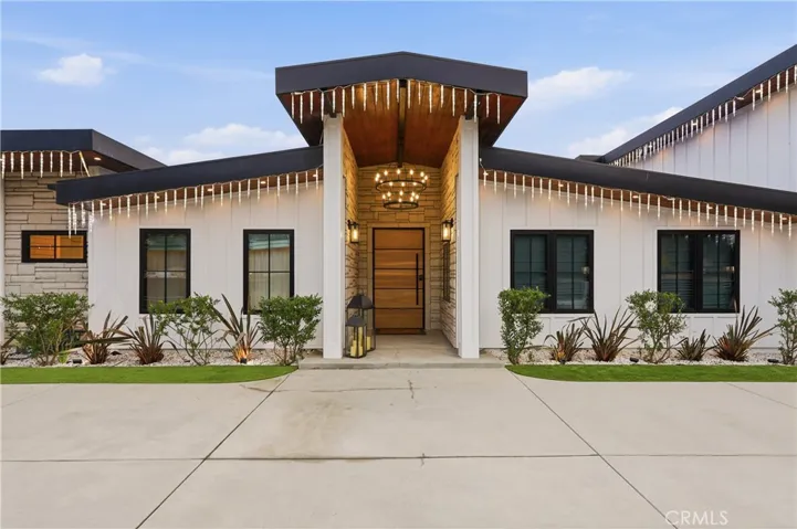 Grand front foyer wrapped in stone with a two-tiered rustic chandelier, complemented by two posts and low maintenance landscape!