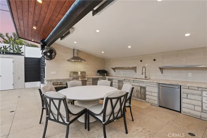 Covered BBQ kitchen w/ 2 electric heaters, electric oven, BBQ, 2 gas burners, sink, dishwasher, ice maker and outdoor fridge.