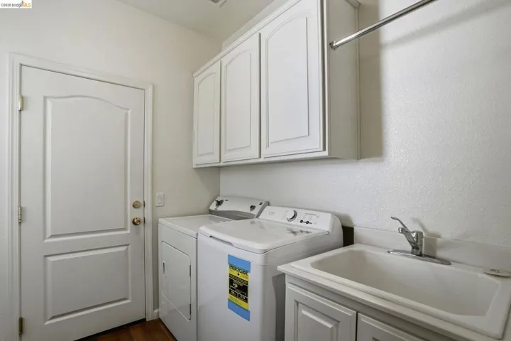 Laundry area featuring cabinet space, independent washer and dryer, a textured wall, and dark wood-type flooring