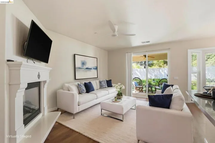 Living room featuring wood finished floors, ceiling fan, and a glass covered fireplace