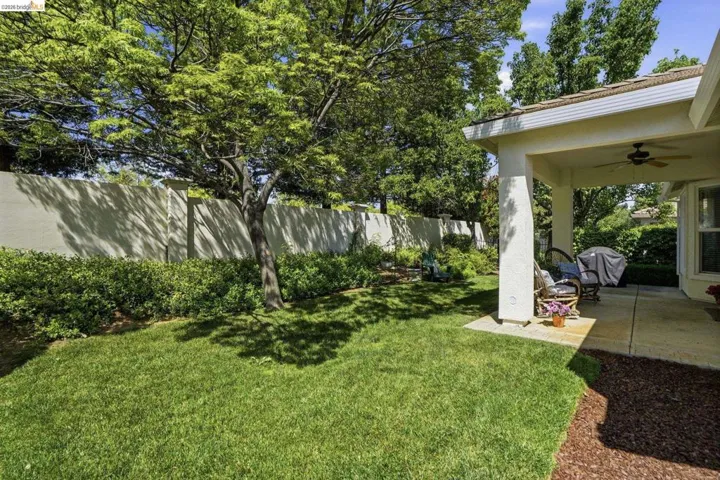 Fenced backyard with a ceiling fan and a patio