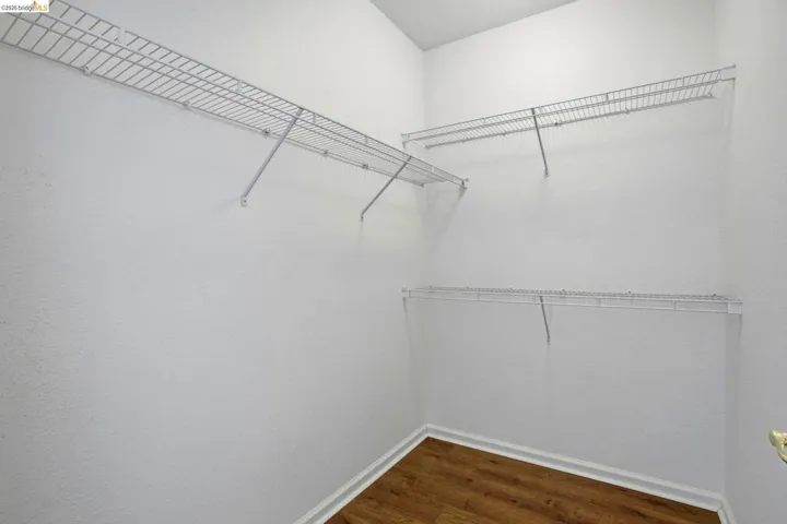 Walk in closet with dark wood-style flooring