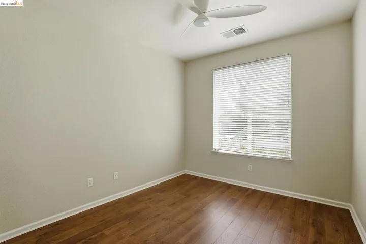 Unfurnished room with dark wood-style floors and a ceiling fan
