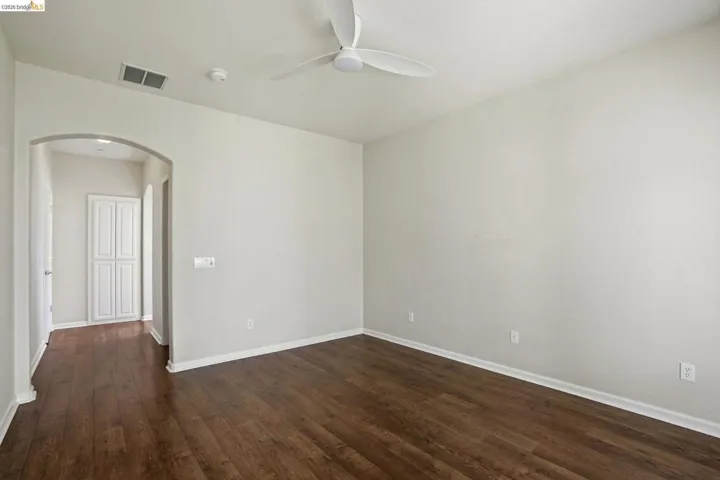 Spare room with arched walkways, dark wood-type flooring, and ceiling fan