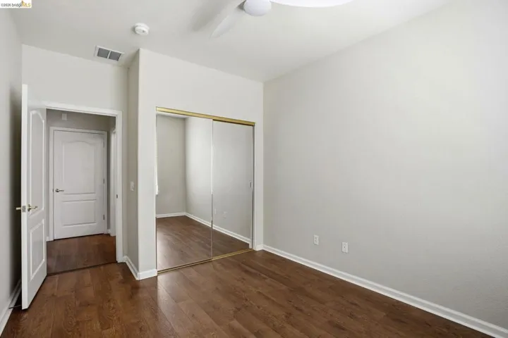 Unfurnished bedroom with dark wood-style flooring, a closet, and ceiling fan
