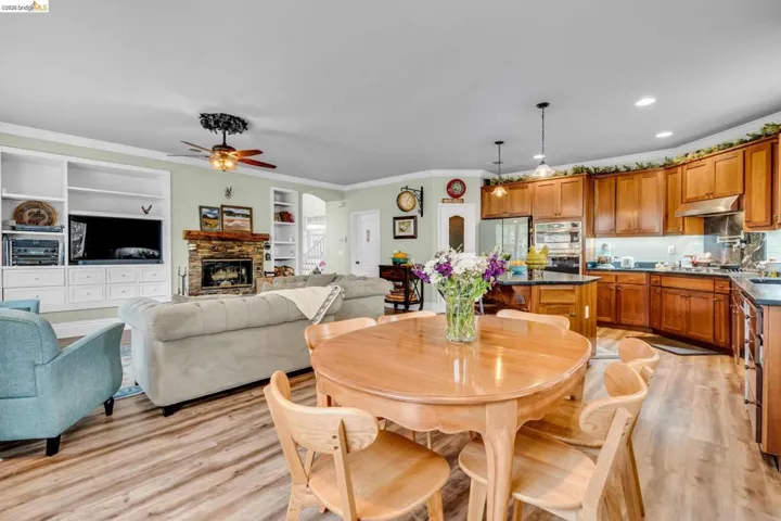 Dining room featuring crown molding, light wood-style flooring, built in features, arched walkways, and ceiling fan