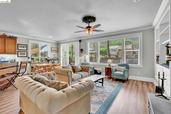 Living room with ornamental molding, light wood finished floors, and ceiling fan