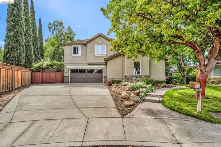 Traditional home with stucco siding, an attached garage, driveway, and stone siding