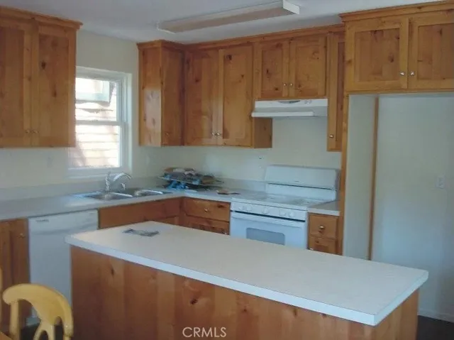 Kitchen with island, & dishwasher. Knotty pine cabinets.