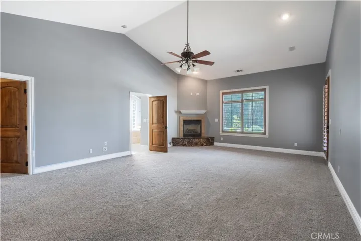 Expansive primary suite with a fireplace and door to the pool