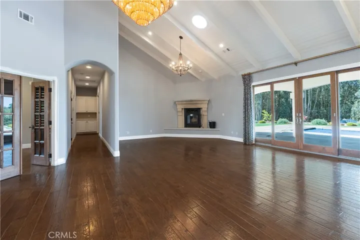 Hallway to the primary suite and fourth bedroom, office to the left and a wall of windows bringing the outside in