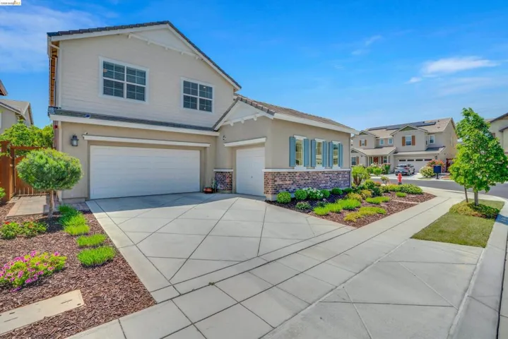 View of front of house with driveway, an attached garage, brick siding, and stucco siding
