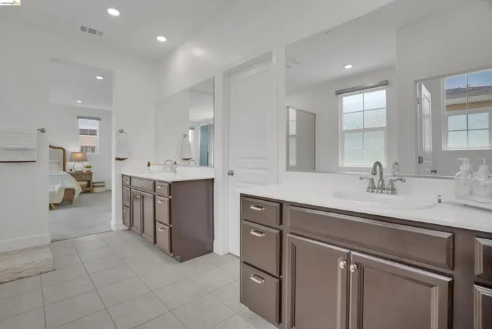Ensuite bathroom with two vanities, plenty of natural light, recessed lighting, and light tile patterned flooring