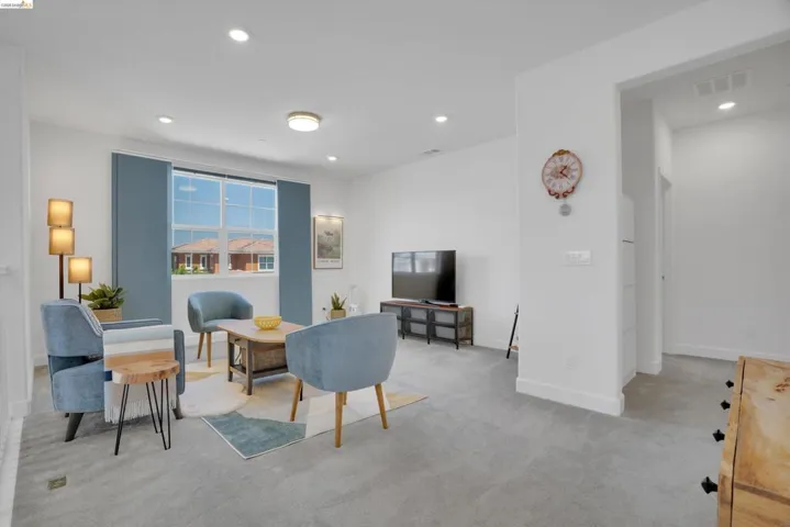 Living area with light carpet and recessed lighting