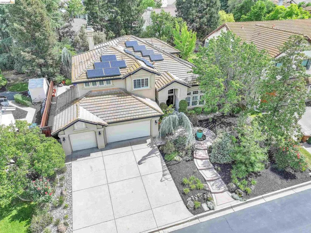 Traditional home with a tile roof, solar panels, driveway, an attached garage, and stucco siding