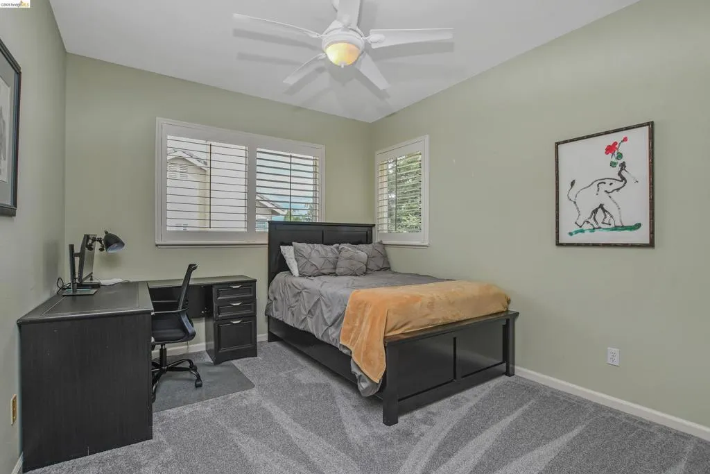 Bedroom featuring carpet flooring, ceiling fan, and a desk
